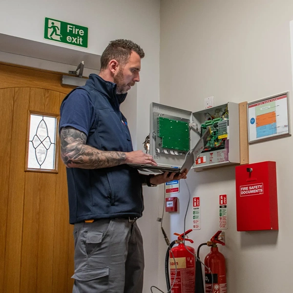 A technician checking a fire alarm control panel