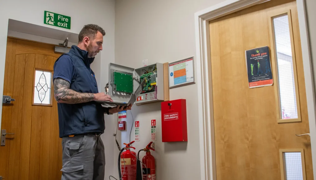 A technician checking a fire alarm control panel