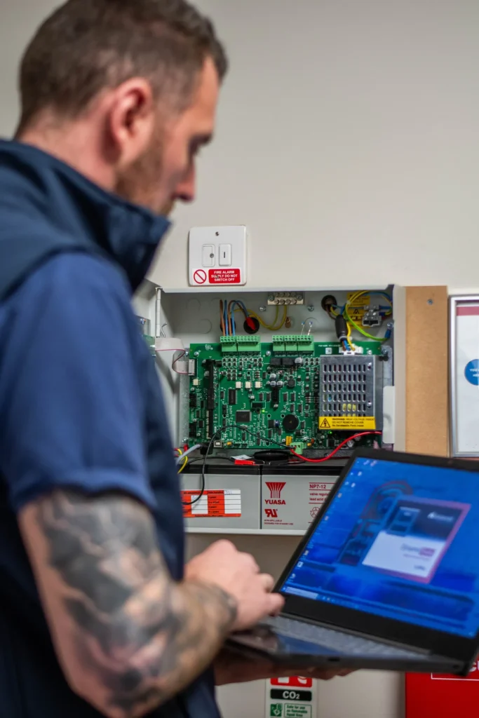 An engineer repairing a fire alarm control panel