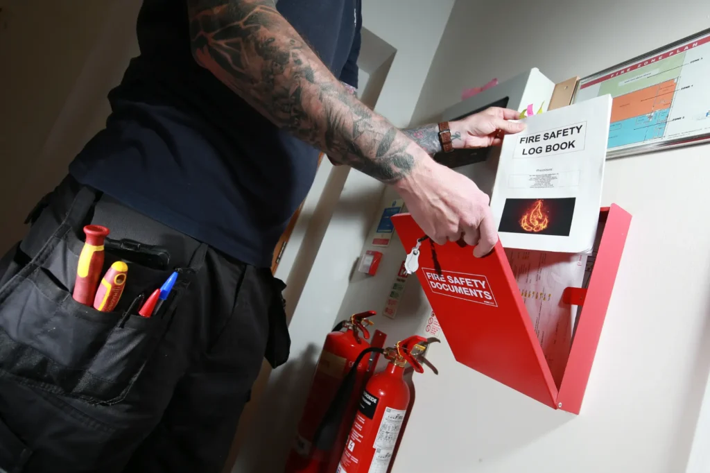 Fire Alarm Systems engineer completing a fire safety log book after a fire alarm service